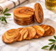 Wooden coasters on a marble surface with olive branches and a glass of oil.