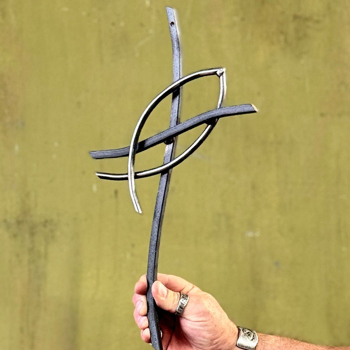 Hand holding a metal sculpture against a green background