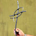 Hand holding a metal sculpture against a green background