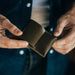 Brown leather wallet held by hands against a blurred background