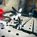 Metallic flower-shaped objects on a perforated metal surface