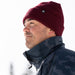 Man wearing a red beanie and dark jacket against a white background