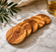 Set of wooden coasters on a marble surface with a glass of whiskey and olive branch.