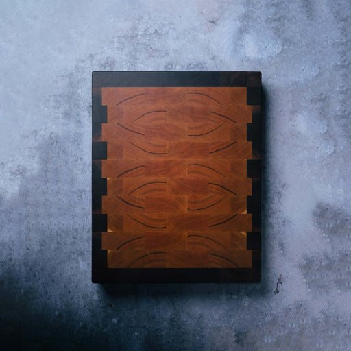 Wooden cutting board with a black border on a textured gray surface