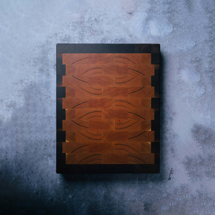 Wooden cutting board with a black border on a textured gray surface