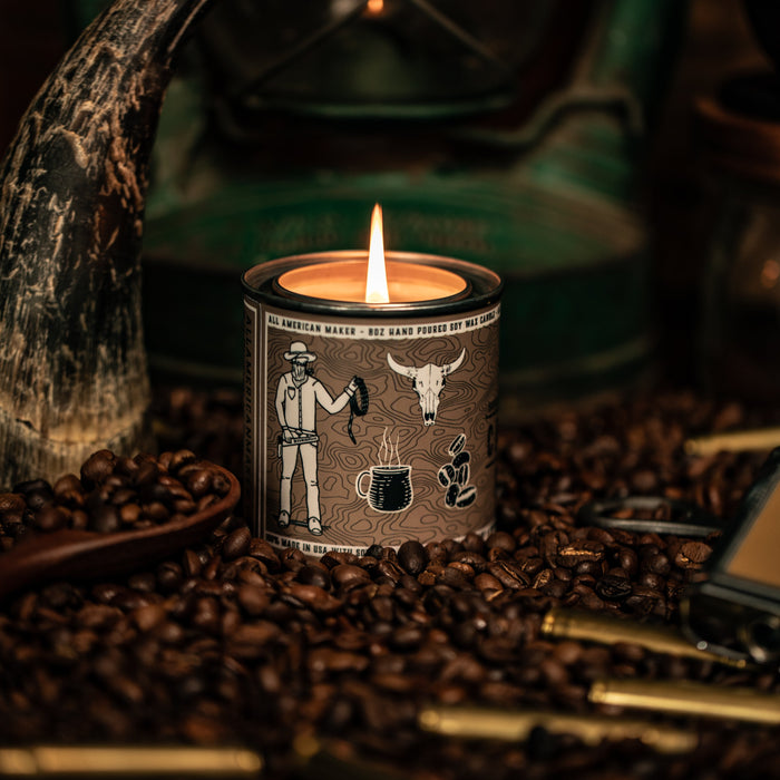Candle in a decorative container with a rustic lantern and coffee beans in the background
