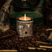 Candle in a decorative container with a rustic lantern and coffee beans in the background
