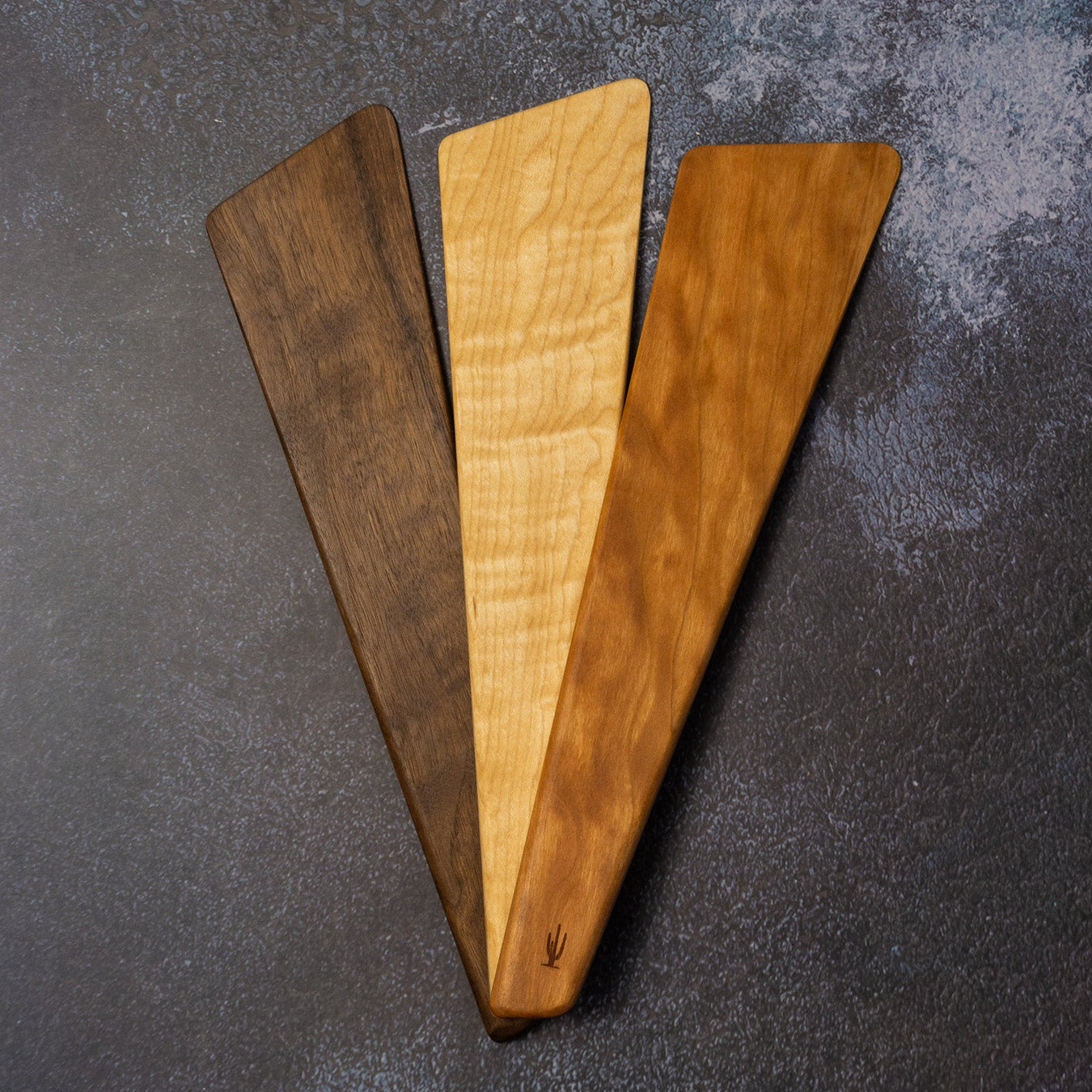 Three wooden cutting boards of different sizes on a dark surface