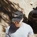 Man wearing a cap and sunglasses in front of a off-road vehicle on a dirt road.