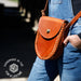 Person wearing a brown leather bag with 'Handmade in the USA for a Lifetime' logo.