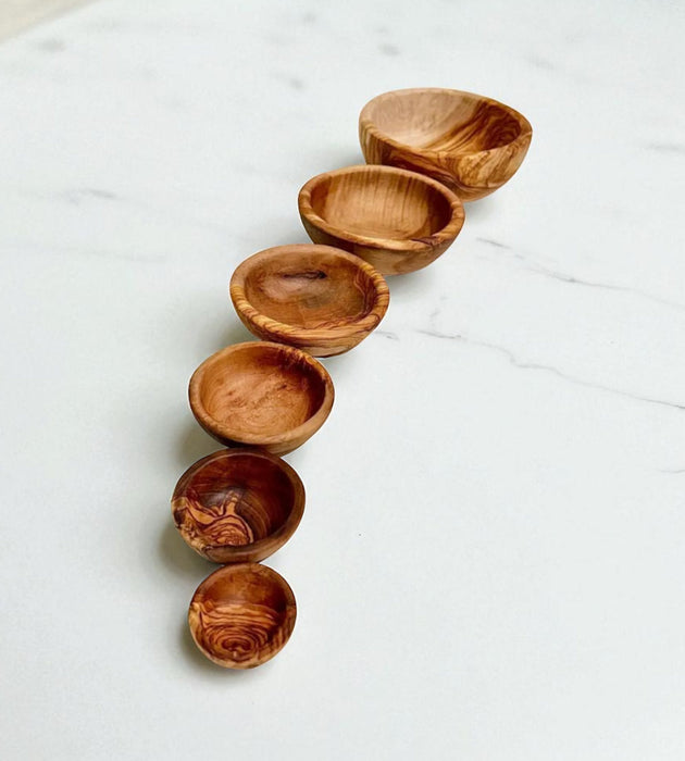 Set of wooden bowls arranged in a curved line on a light surface
