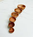 Set of wooden bowls arranged in a curved line on a light surface