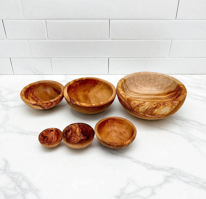 Set of wooden bowls on a marble surface with a white tiled wall background