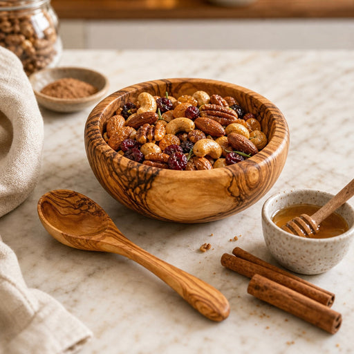 Wooden bowl filled with a mixed nut and seed trail mix on a marble surface with a wooden spoon and honey dipper.