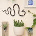 Decorative wall with plants, a snake sculpture, and a framed picture.