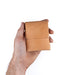 Hand holding a small brown leather wallet against a white background