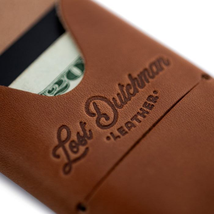 Brown leather money clip with 'Lost Dutchman Leather' branding on a white background