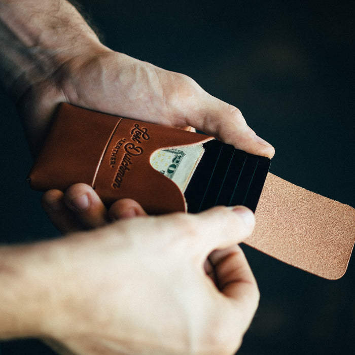 Person holding a brown leather wallet with money against a dark background