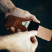 Person holding a brown leather wallet with money against a dark background