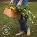 Person holding a woven basket with flowers outdoors, featuring 'Handmade in the USA for a Lifetime' logo.