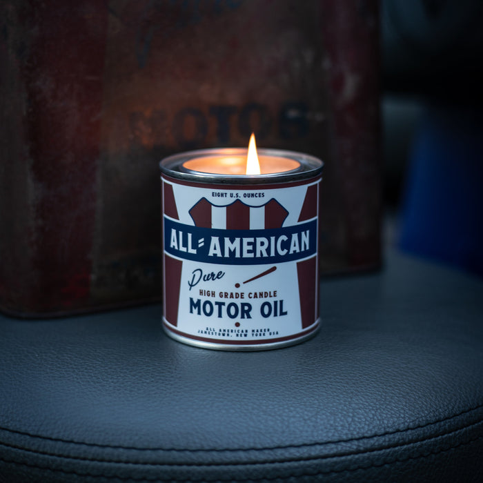 Candle in a container labeled 'All-American Pure Motor Oil' with a vintage feel.