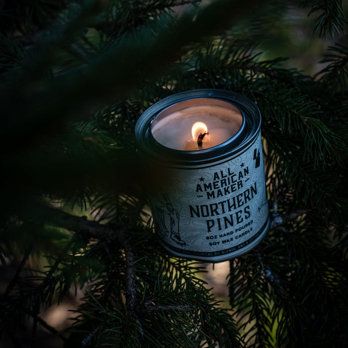 Candle in a can labeled 'Northern Pines' inside a pine tree