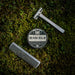 Beard balm container, comb, and razor on a grassy background