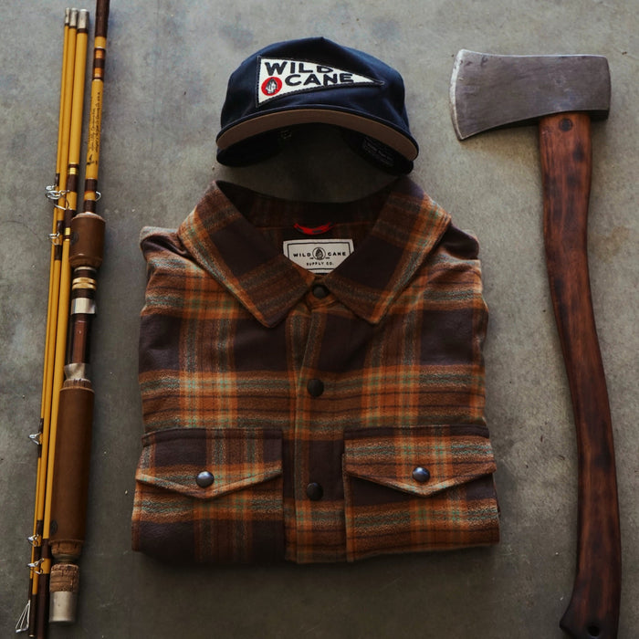 Fishing rod, plaid shirt, cap, and axe on a concrete surface
