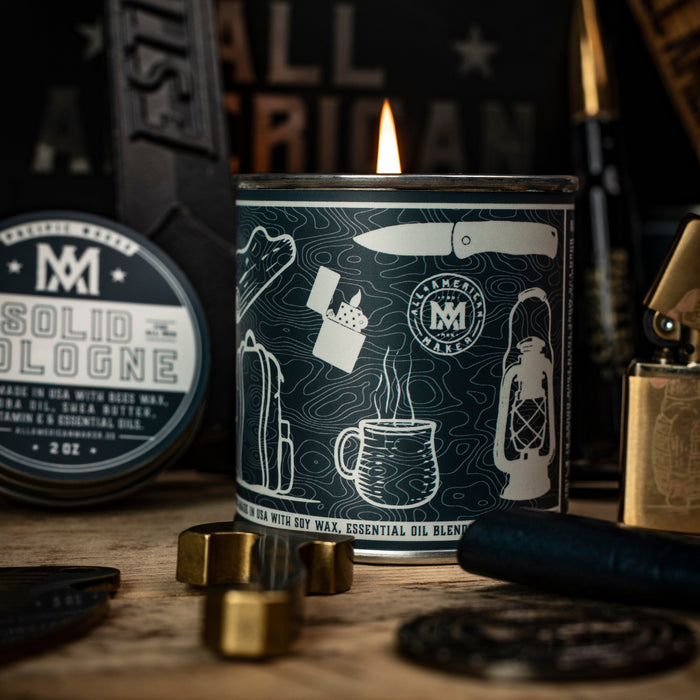 Candle with branding and illustrations on a wooden surface with tools in the background