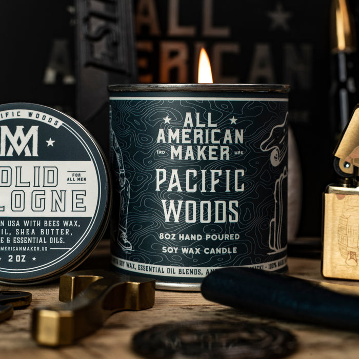 Candle labeled 'All American Maker Pacific Woods' with solid cologne and other items on a wooden surface.