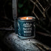 Candle in a 'Pacific Woods' container with a knife on a wooden surface
