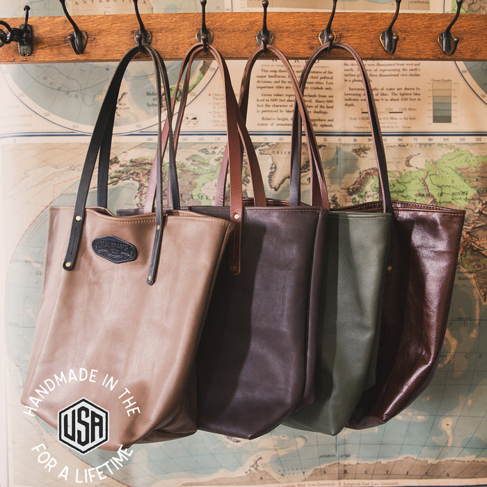 Three leather handbags hanging on a rack with a map background.