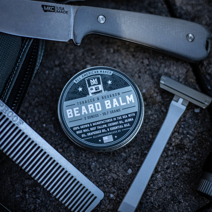 Beard balm container with a knife, comb, and razor on a textured surface