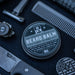 Beard balm container with grooming tools on a dark surface
