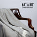 Gray blanket draped over a wooden armchair with dimensions displayed.