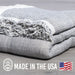 Stack of gray textured blankets with 'Made in the USA' label on a gray background