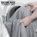 Person taking a gray towel out of a washing machine with text 'Machine Wash Tumble Dry'.