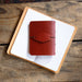 Red leather notebook cover on an open notebook with lined paper, on a wooden surface.