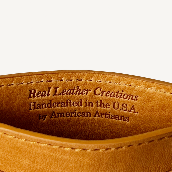 Close-up of brown leather with 'Real Leather Creations' text on a white background
