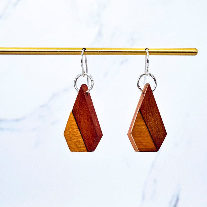 Wooden earrings on a gold rod against a marble background