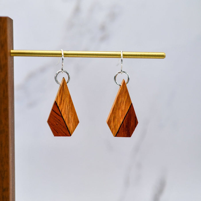Wooden geometric earrings on a gold earring stand against a white background