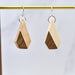Wooden earrings with a geometric design hanging on a gold rod against a white background.