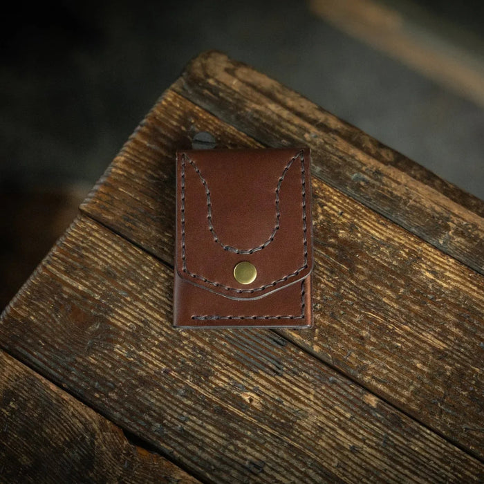 Brown leather wallet with a gold button on a wooden surface