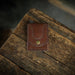 Brown leather wallet with a gold button on a wooden surface