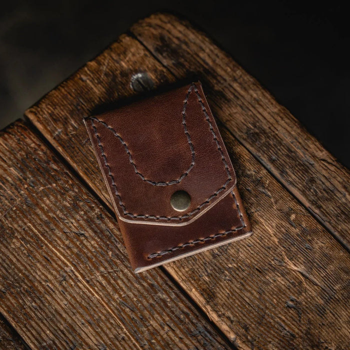 Brown leather wallet on a wooden surface with a dark background