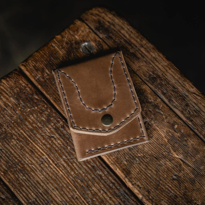 Brown leather wallet on a wooden surface with a dark background