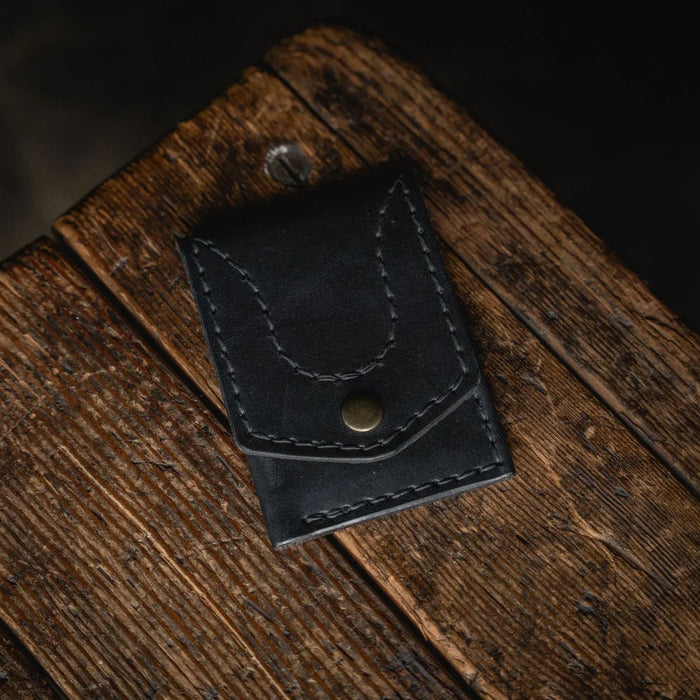 Black leather wallet on a wooden surface with a dark background