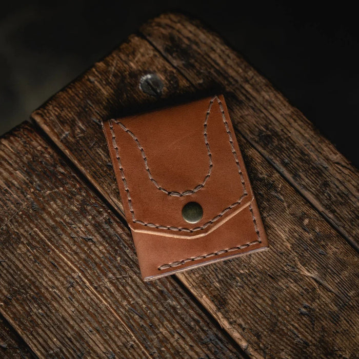 Brown leather pouch with stitching detail on a wooden surface