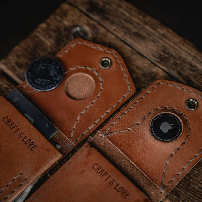Brown leather key holder with metal keyring on a wooden surface