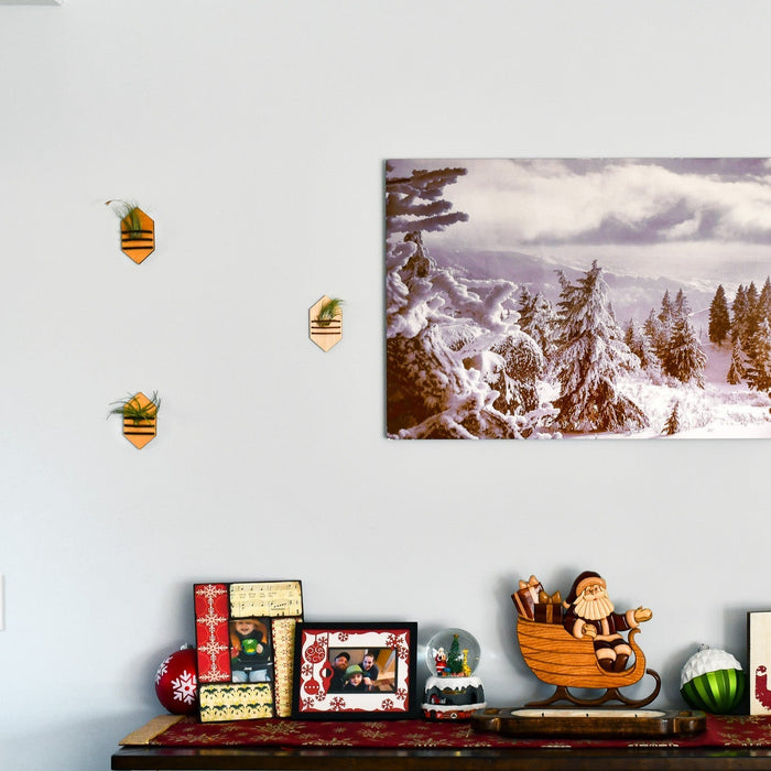 Decorative shelf with Christmas-themed items against a white wall with a snowy landscape print.